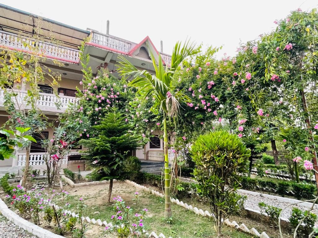 a garden in front of a building with flowers at Hotel Tree Tops- A Serene Friendly Hotel in Sauraha in Chitwan