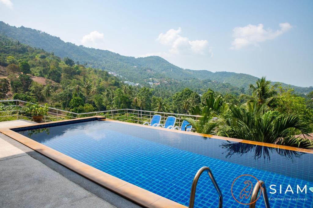 a resort swimming pool with mountains in the background at Chaweng Hill 2Br in Koh Samui