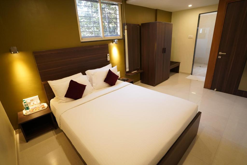 Un dormitorio con una gran cama blanca y una ventana en Hotel Metropolis en Hubli