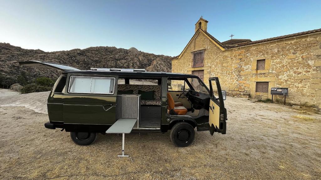 a green jeep parked in front of a building at Camper en Guadarrama in Manzanares el Real