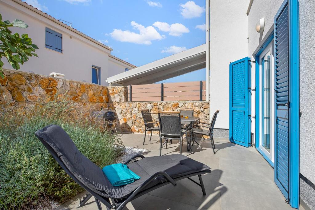 a patio with chairs and a table and a stone wall at Apartment Sunshine Cres in Cres