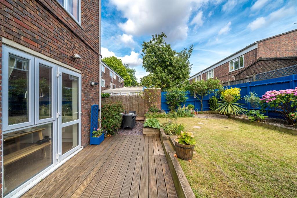 a garden with a wooden deck next to a building at ALTIDO Striking flat with charming garden in London