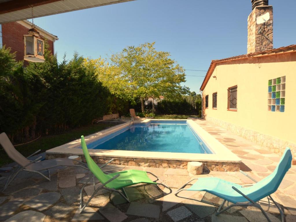 a swimming pool with two lawn chairs next to a house at Villa Brigitte private pool 10 kms LLoret de mar in Maçanet de la Selva