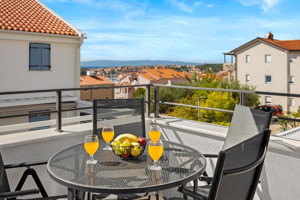 a table with wine glasses and a bowl of fruit on a balcony at Apartments Tim & Klara - Sunny Cres Island in Cres
