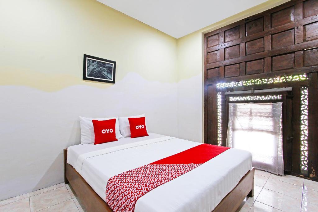 a bedroom with a bed with red pillows on it at Super OYO 3693 Kopi Klotok Homestay Syariah in Magelang