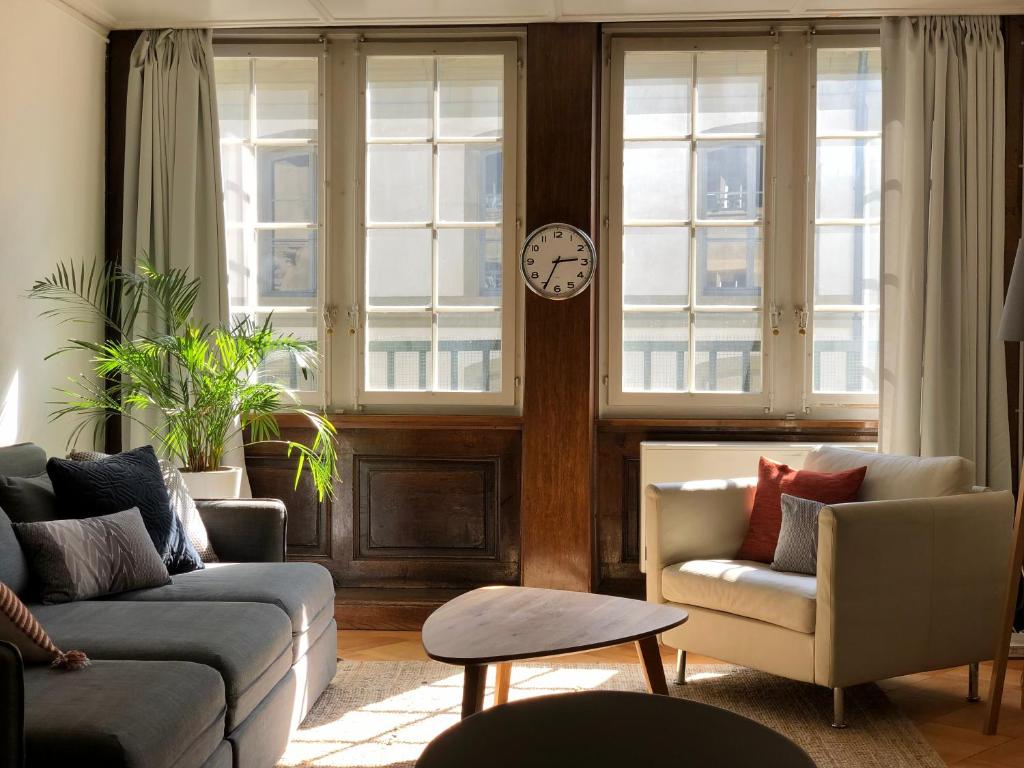 a living room with a couch and a clock on a wall at Historical and Modern Flat by Zytglogge - 2nd floor in Bern