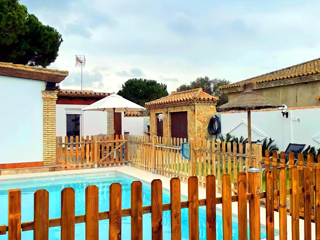 una valla de madera junto a una piscina con una casa en Casa piscina Privada Vallada & Barbacoa A&C, en Chiclana de la Frontera