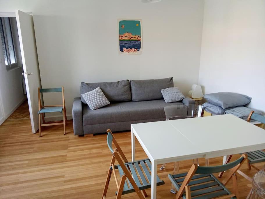 a living room with a couch and a table and chairs at charmante maison près du centre ville in Amboise