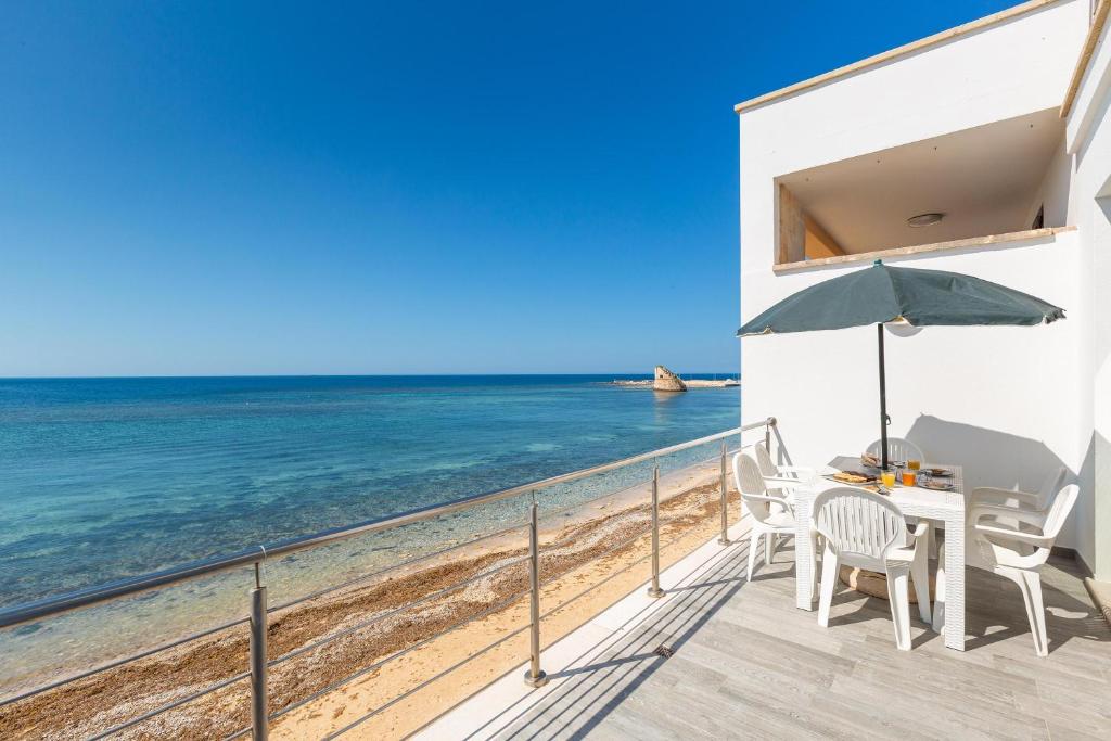 eine Terrasse mit Stühlen und einem Sonnenschirm am Strand in der Unterkunft Un sogno sul mare by BarbarHouse in Torre Pali 