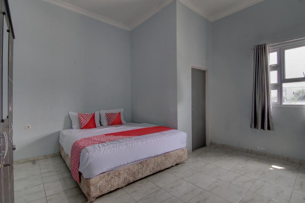 - une chambre avec un lit doté d'oreillers rouges dans l'établissement OYO 92806 Penginapan Geby Syariah, à Pekanbaru