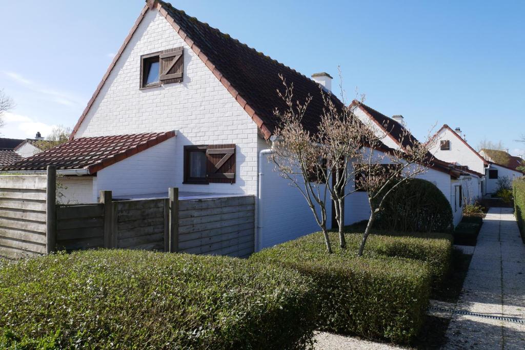 uma casa branca com uma cerca e um quintal em Zeepolder I 38 em De Haan