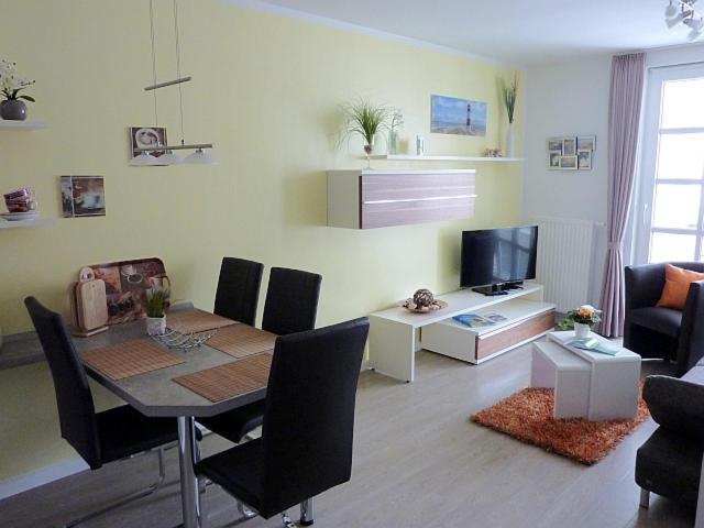 ein Wohnzimmer mit einem Tisch, Stühlen und einem TV in der Unterkunft Residenz am Balmer See - BS 58 mit Wellnessbereich in Balm