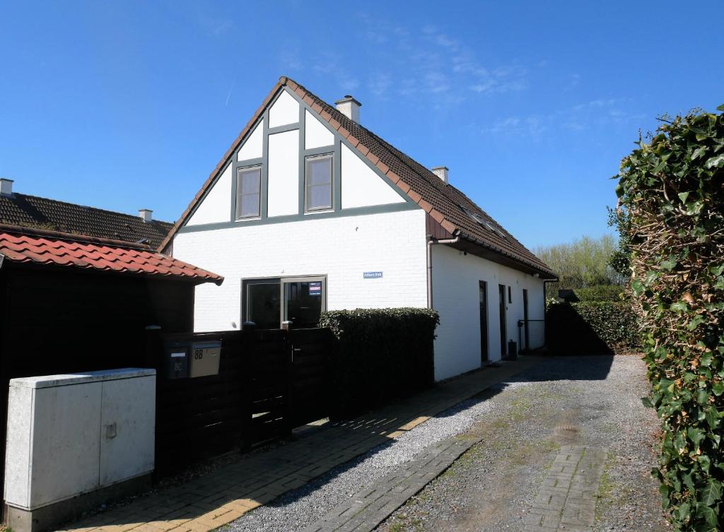 una casa bianca con tetto rosso e vialetto di Achter N Diek a De Haan