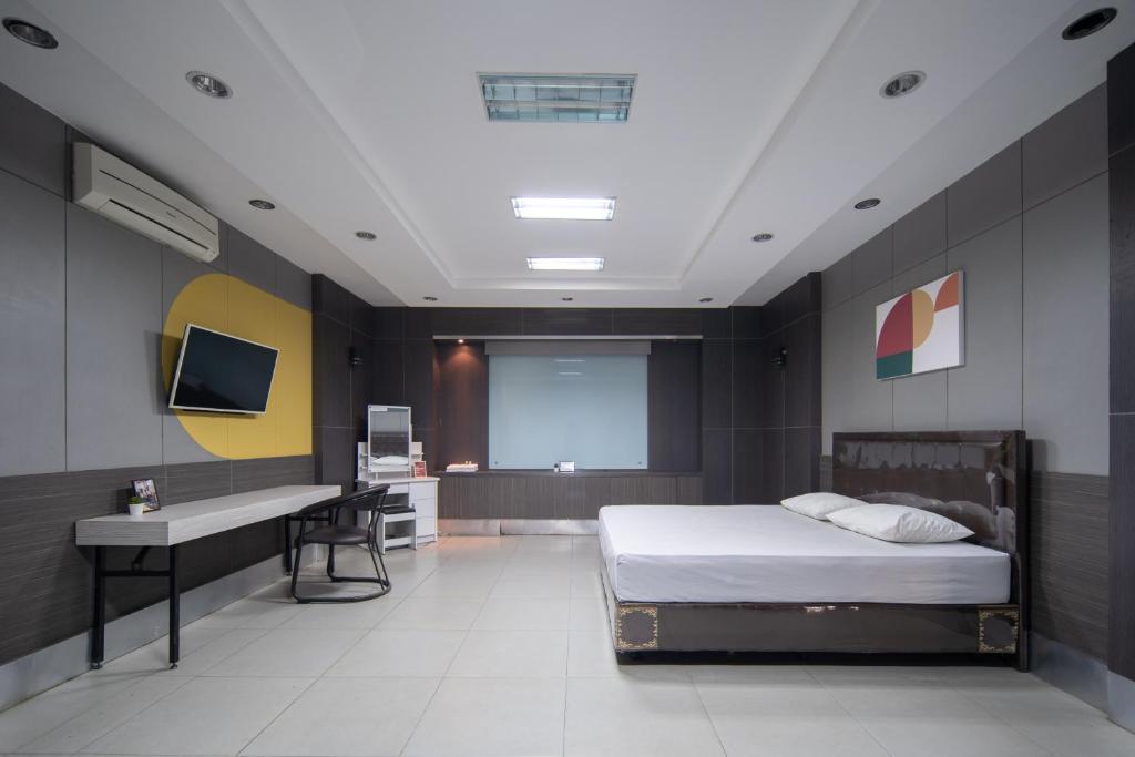 um quarto com uma cama, uma secretária e uma televisão em Cove Sky City Home em Bandung