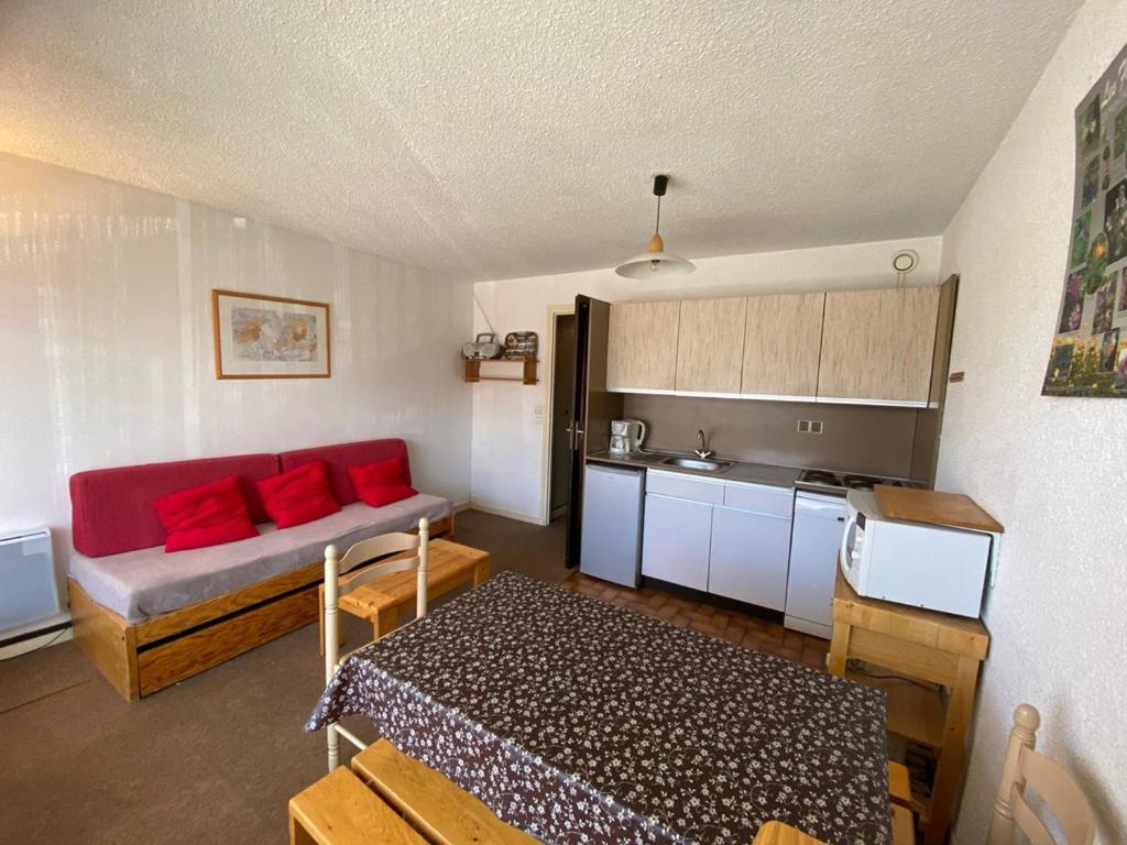 a living room with a red couch and a kitchen at Appartement Huez, 1 pièce, 4 personnes - FR-1-405-48 in L'Alpe-d'Huez