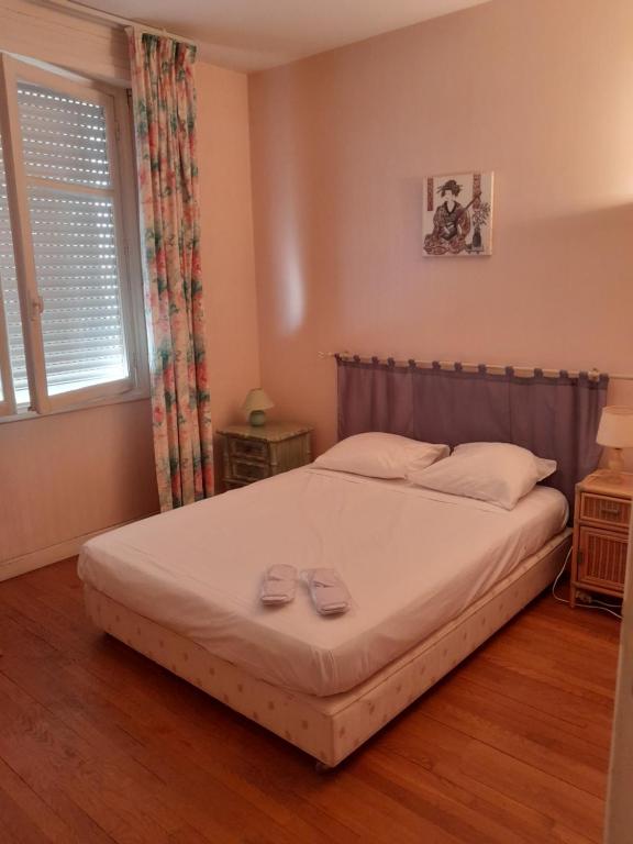 une chambre avec un lit avec deux pantoufles dessus dans l'établissement Georges Clémenceau Appartment Cannes, à Cannes