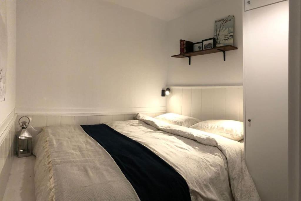 a white bedroom with a large bed and a shelf at Bleuets II in Sainte-Léocadie