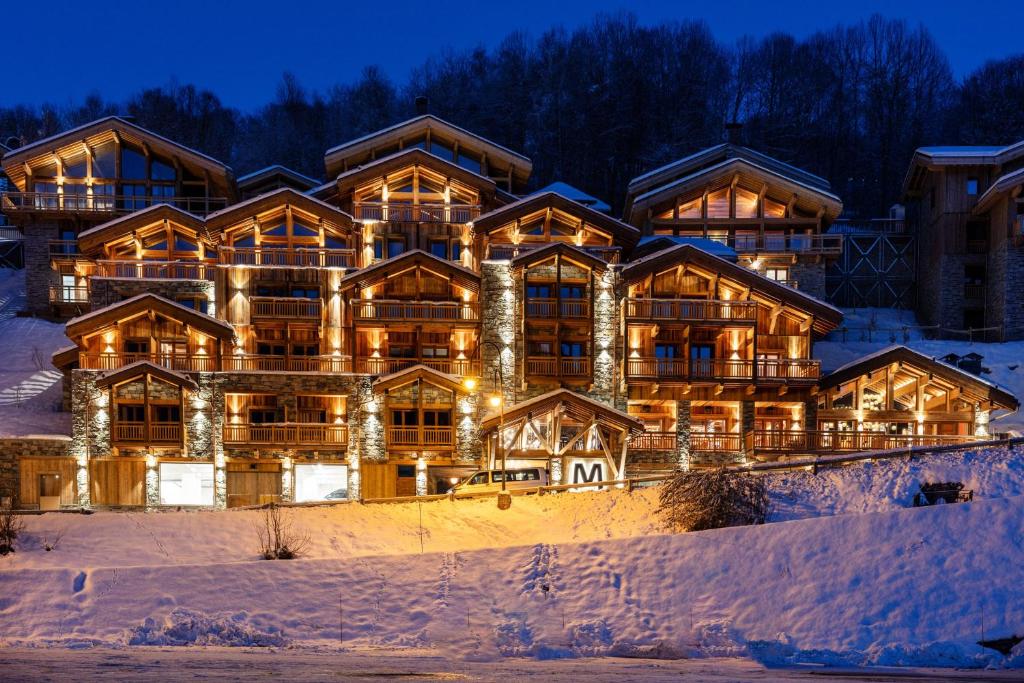 a large log home in the snow at night at M Lodge & Spa in Saint-Martin-de-Belleville