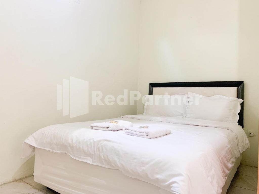 uma cama branca com duas toalhas em cima em Oma Uti Syariah Mitra RedDoorz near Stasiun Lempuyangan em Sentool