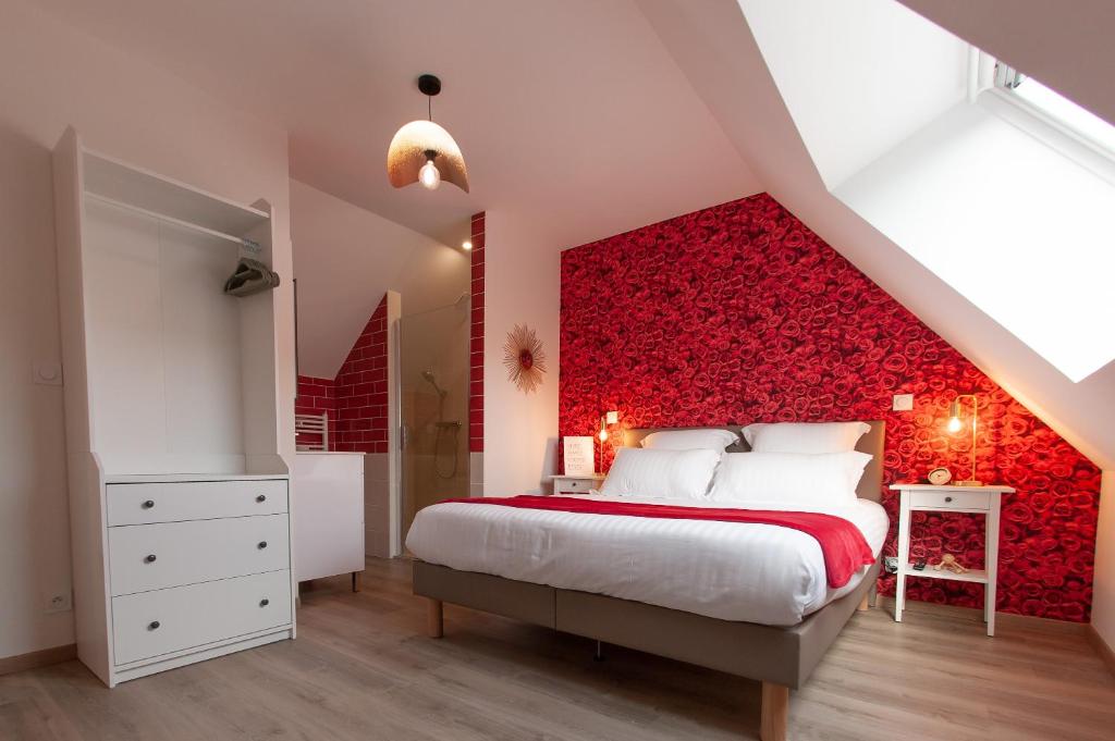 Un dormitorio con una pared de acento rojo y una cama en Les clés de la ferme - 4 chambres - proche La Loupe et Nogent-le-Rotrou - option SPA, en Sablons-sur-Huisne