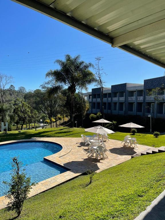 a swimming pool with umbrellas and chairs and a building at DR Hotel Rio Branco do Sul in Votuverava