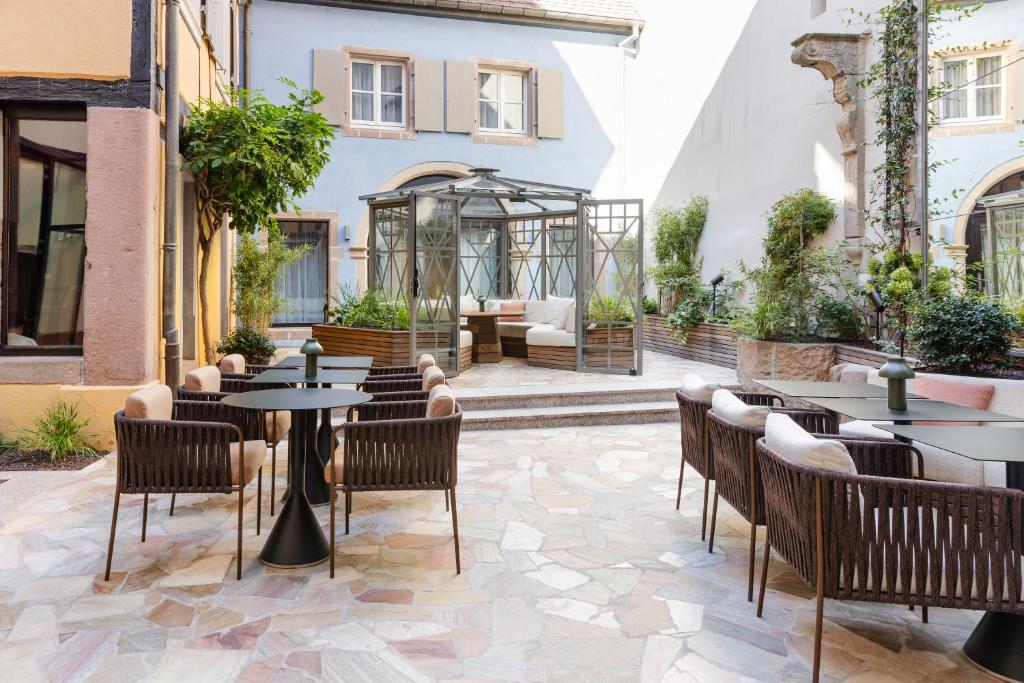 a patio at a restaurant with tables and chairs at Hotel Le Colombier in Colmar