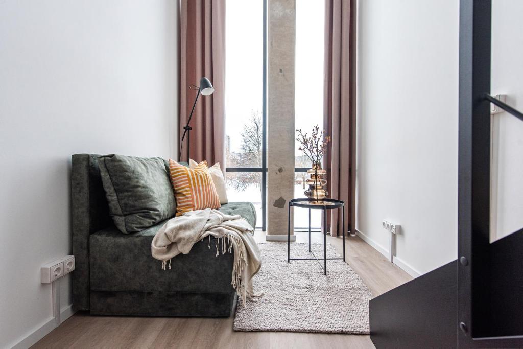 a living room with a green couch and a window at We LOFT in Vilnius