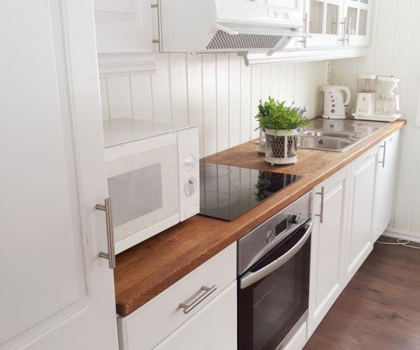 a kitchen with white cabinets and a wooden counter top at FjellRo 
