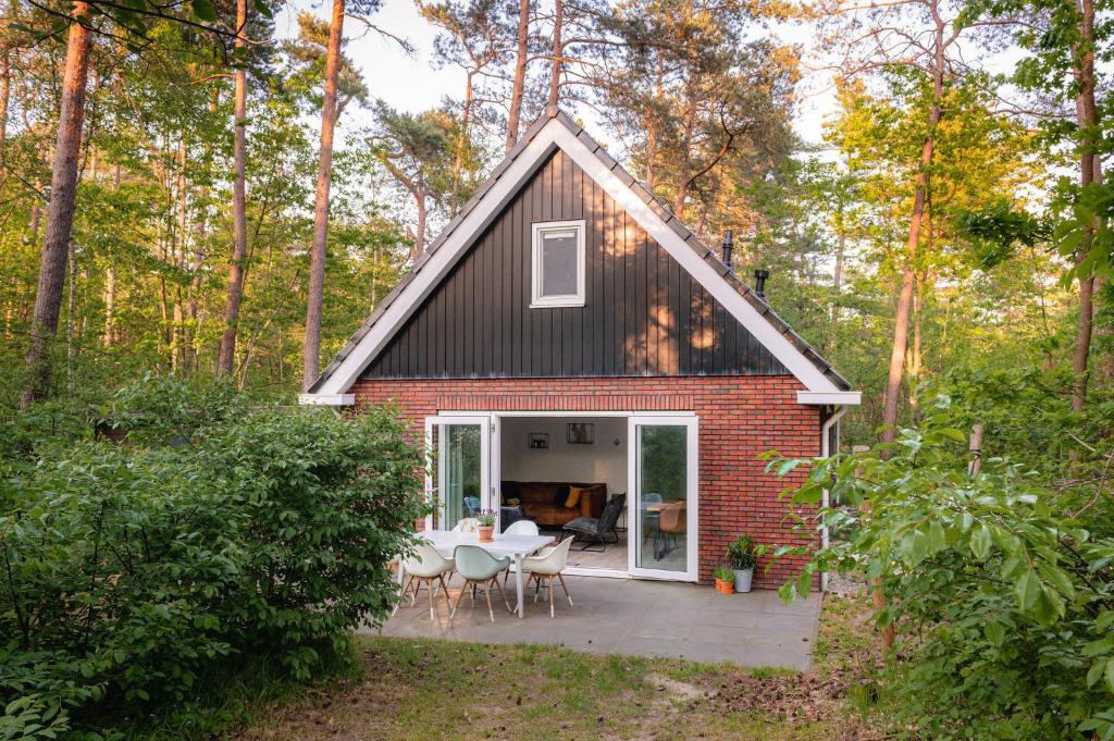 een klein huis met een patio in het bos bij Luxe Vakantiehuis Grove Den Veluwe in Nunspeet