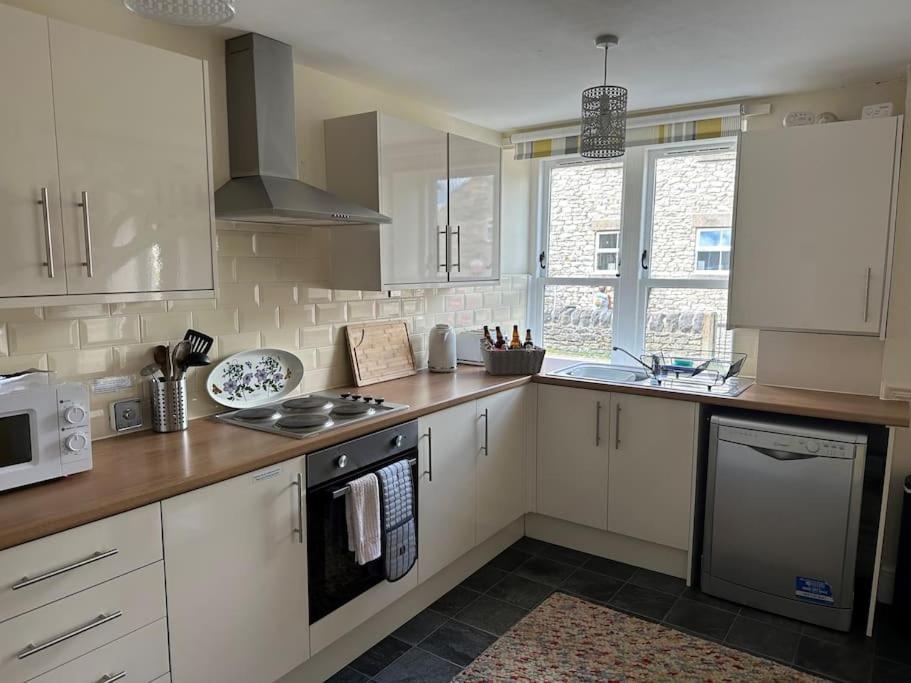 a kitchen with white cabinets and a stove top oven at Trotters Place - Bradwell in Bradwell