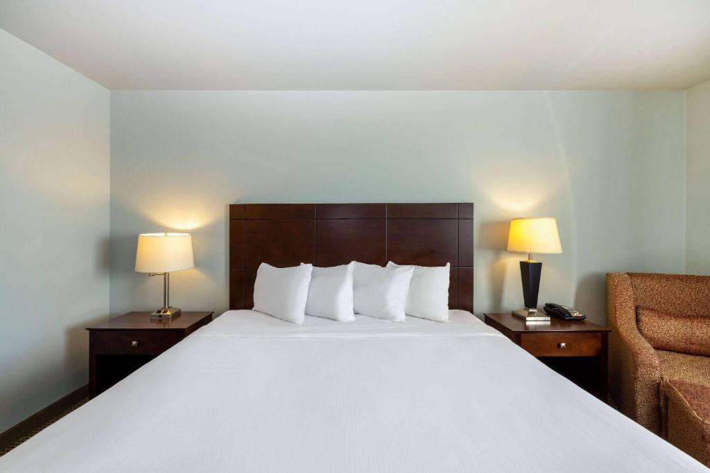 a hotel room with a large bed and a chair at Baymont by Wyndham Rapid City in Rapid City