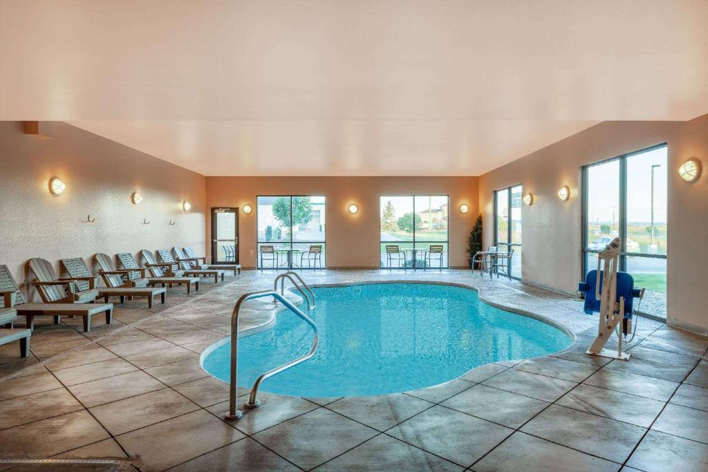 a pool in a hotel room with tables and chairs at Baymont by Wyndham Rapid City in Rapid City