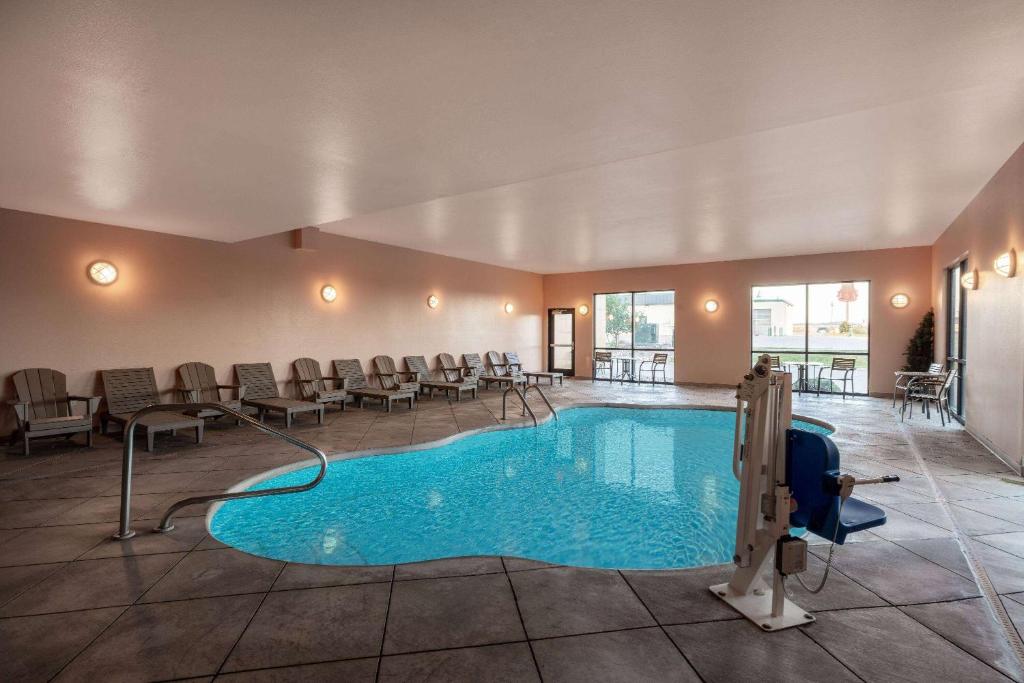 a pool in a hotel lobby with chairs and tables at Baymont by Wyndham Rapid City in Rapid City