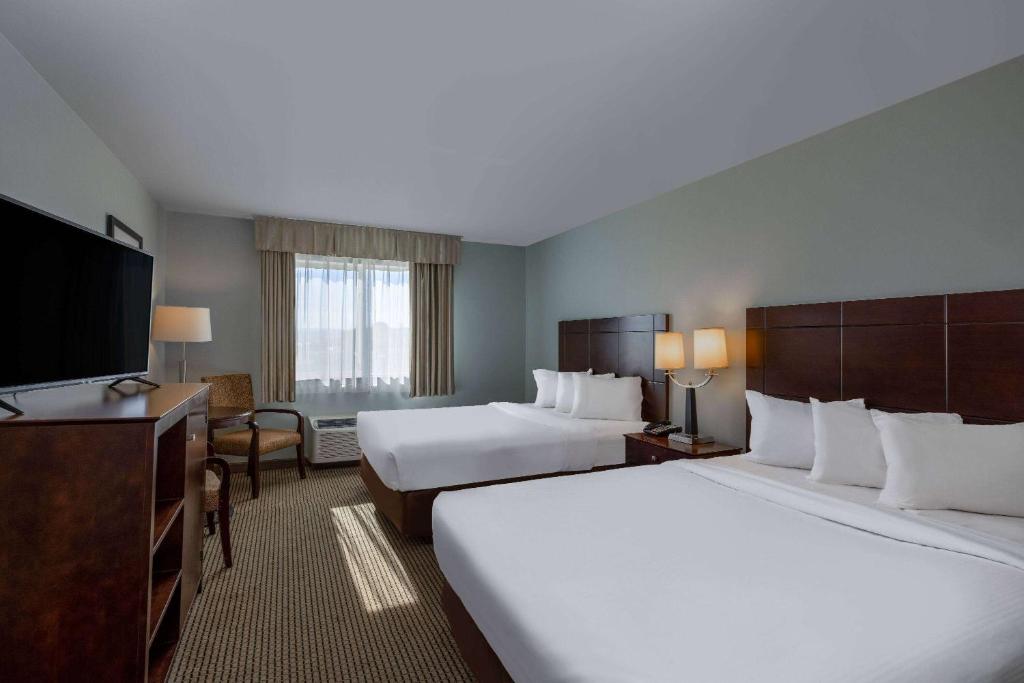 a hotel room with two beds and a flat screen tv at Baymont by Wyndham Rapid City in Rapid City