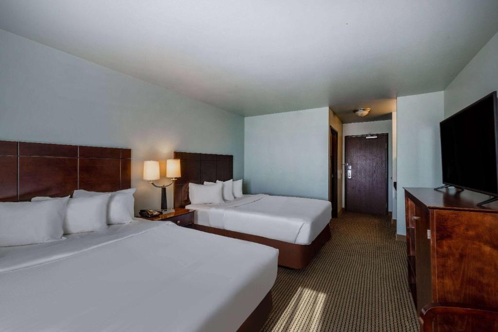a hotel room with two beds and a flat screen tv at Baymont by Wyndham Rapid City in Rapid City