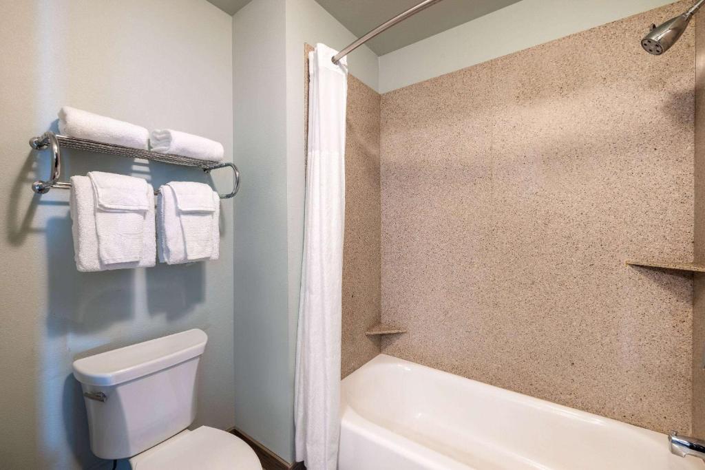 a bathroom with a white toilet and a bath tub at Baymont by Wyndham Rapid City in Rapid City
