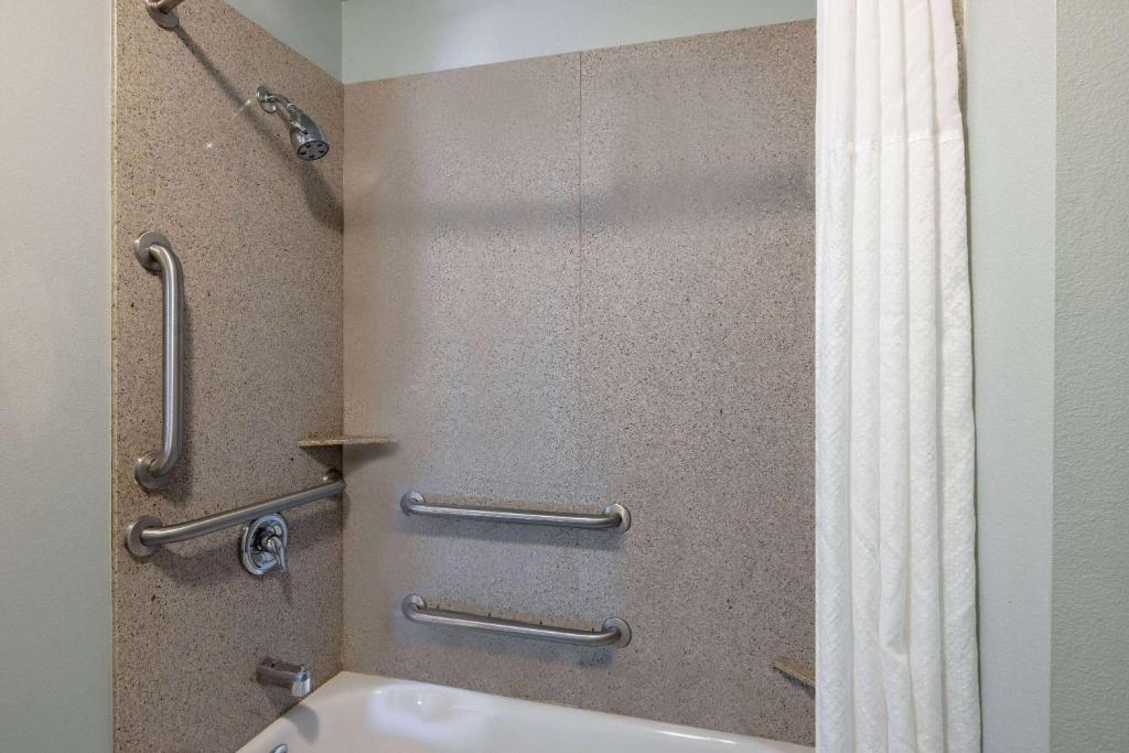 a bathroom with a shower with a toilet and a shower curtain at Baymont by Wyndham Rapid City in Rapid City
