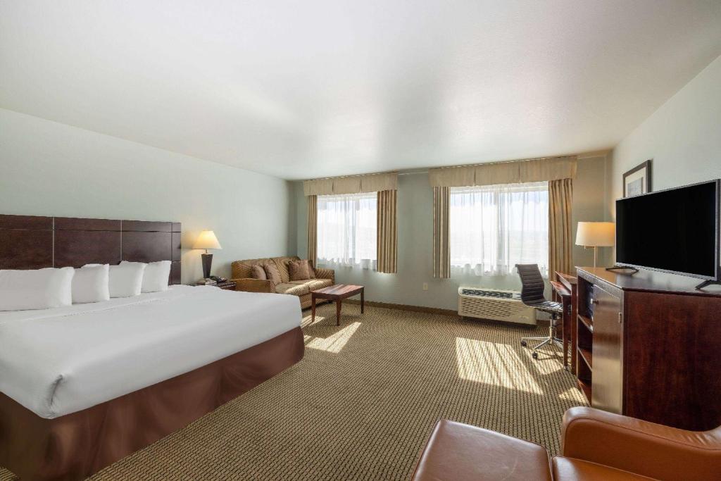 a hotel room with a large bed and a flat screen tv at Baymont by Wyndham Rapid City in Rapid City