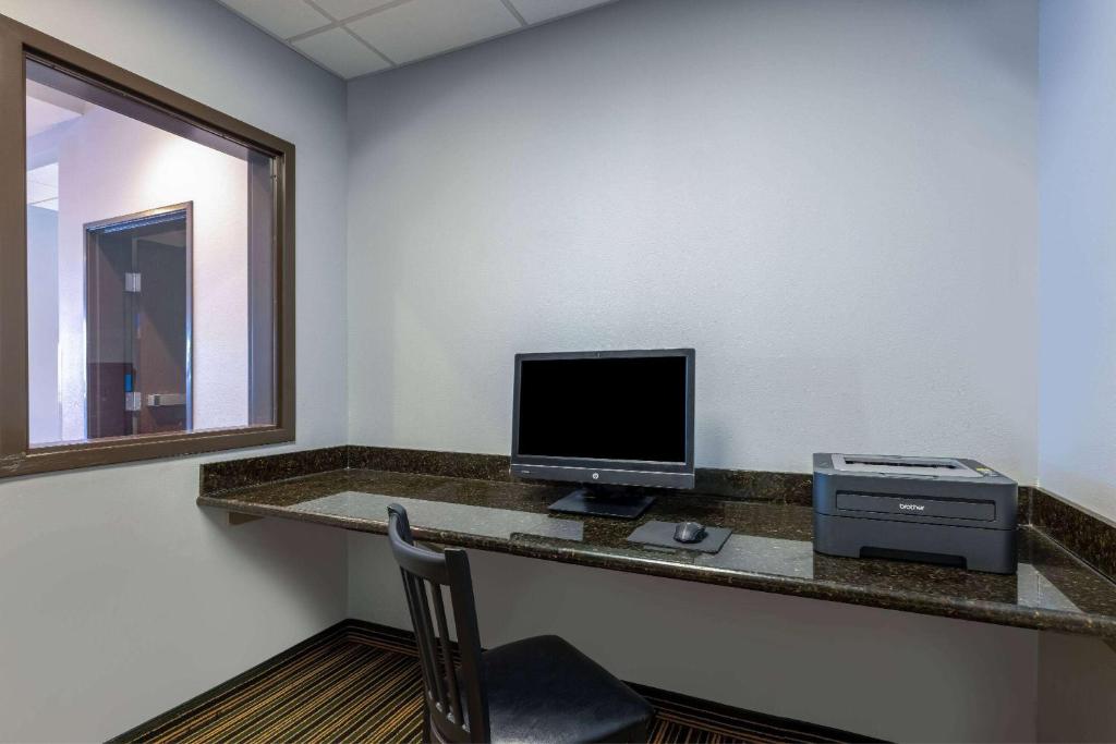 a room with a desk with a computer and a monitor at Baymont by Wyndham Rapid City in Rapid City