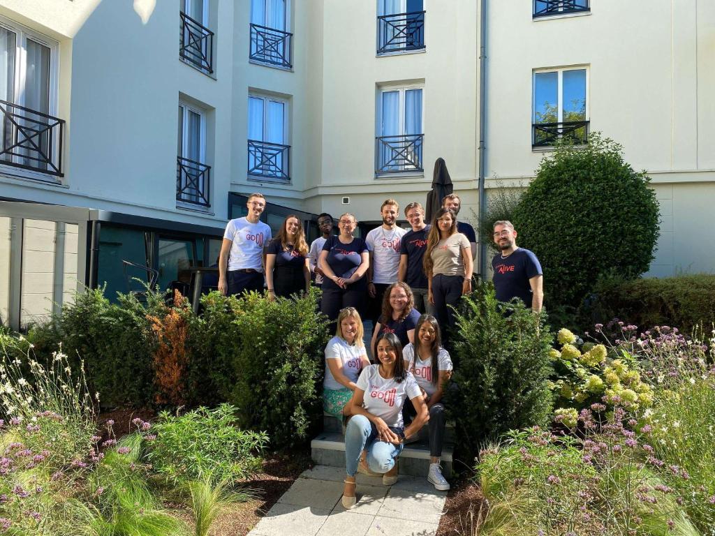 un grupo de personas de pie en frente de un edificio en ibis Valenciennes, en Valenciennes