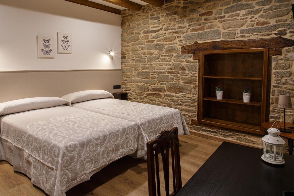1 dormitorio con cama y pared de ladrillo en Casa Baran, en Sarria