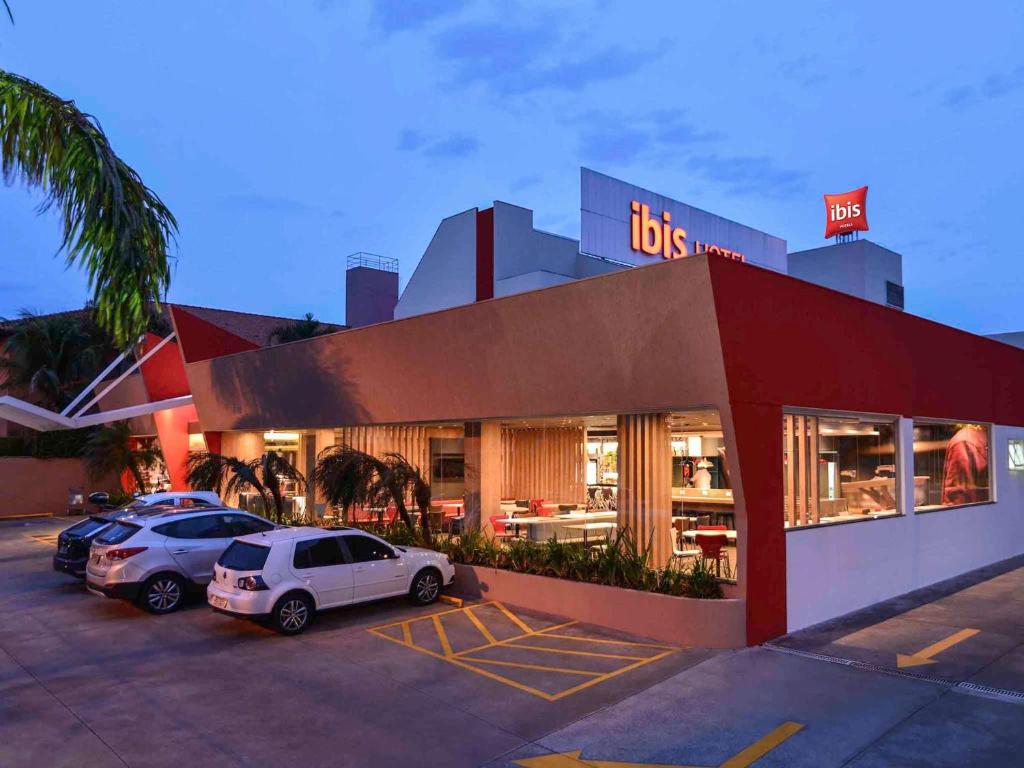 dos coches estacionados en un estacionamiento frente a un restaurante en ibis Campo Grande, en Campo Grande