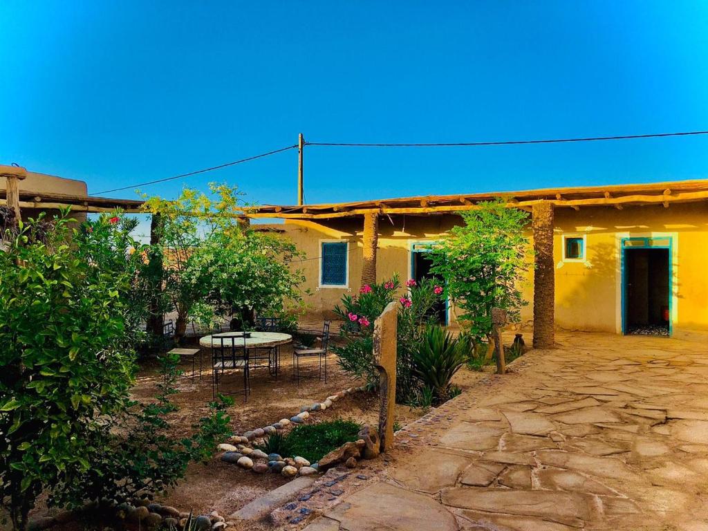ein Haus mit einer Terrasse und einem Tisch davor in der Unterkunft Dar Oasis Moringa in Merzane