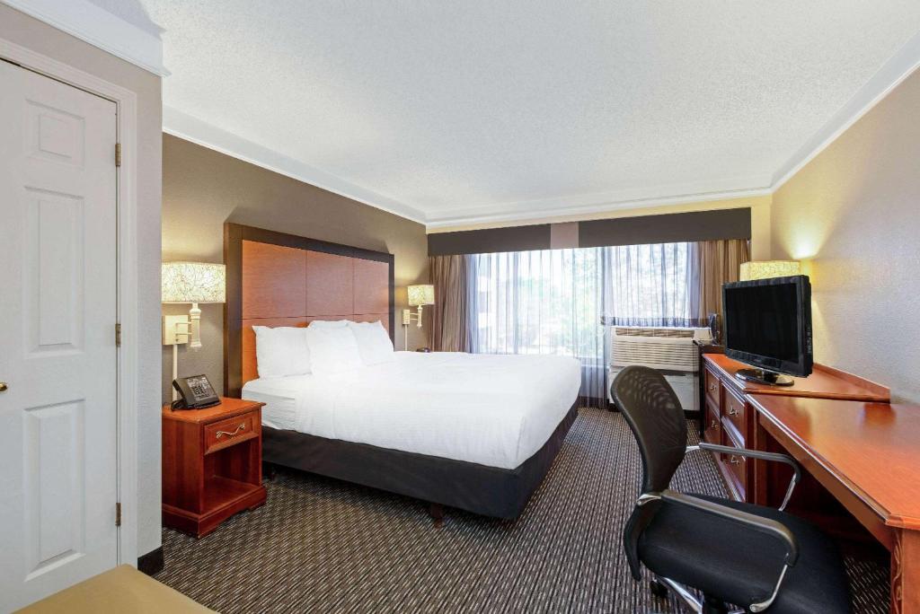 a hotel room with a bed and a desk with a computer at La Quinta by Wyndham New Orleans Airport in Kenner