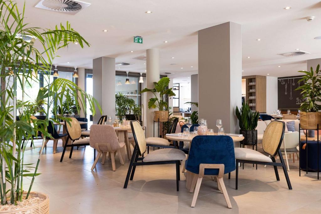 un restaurant avec des tables, des chaises et des plantes dans l'établissement Hilton Garden Inn Tours Centre, France, à Tours