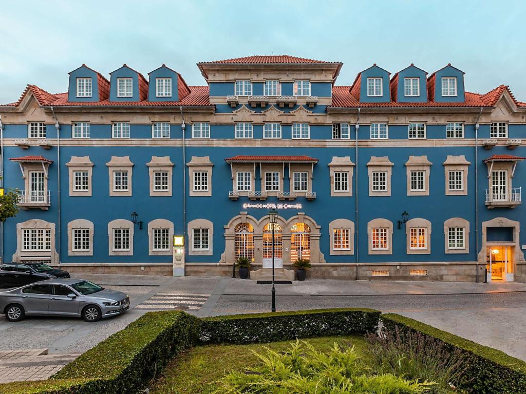 un edificio azul con un coche aparcado delante de él en ibis Styles Chaves en Chaves