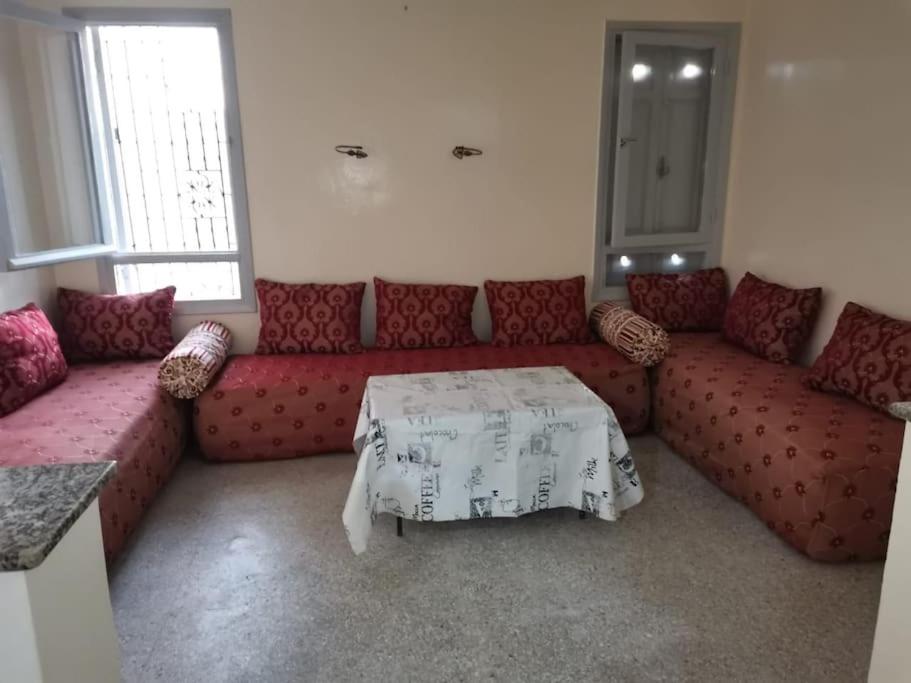 a living room with a red couch and a table at Appartement 70m 2 à 2 min de la gare de Safi in Safi