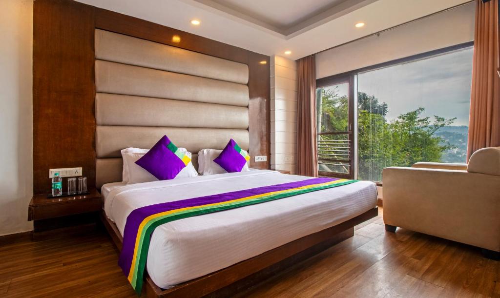 a bedroom with a large bed and a large window at Treebo Tryst Queen Of Hills Near Mall Road in Mussoorie