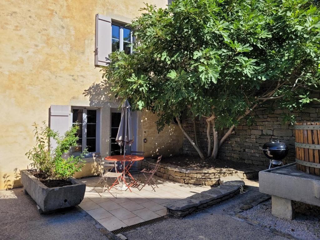 un patio con una mesa y un árbol frente a un edificio en L'Alambic à Martial, en Ménétru-le-Vignoble