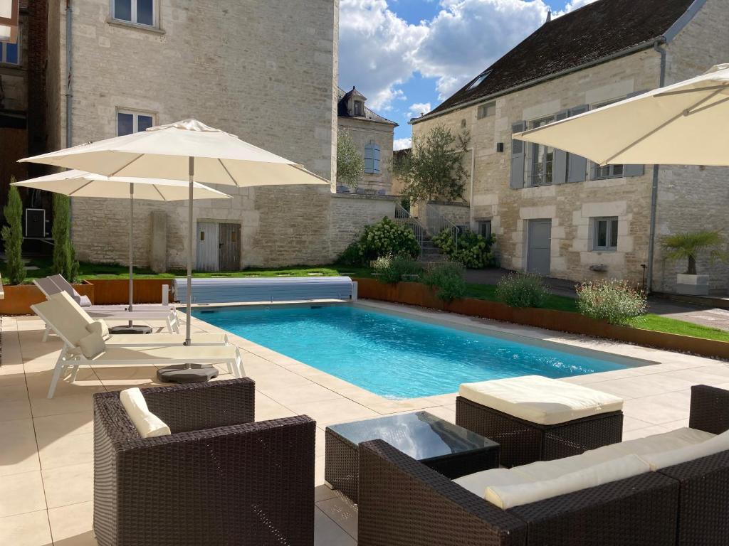 a swimming pool with chairs and umbrellas next to a building at Le Clos des Riceys - La Villa Lombardi in Les Riceys